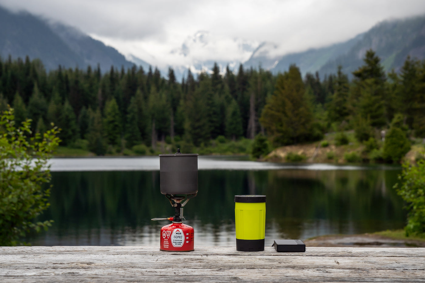 Electric camping stove and battery next to traditional gas camping stove and pot