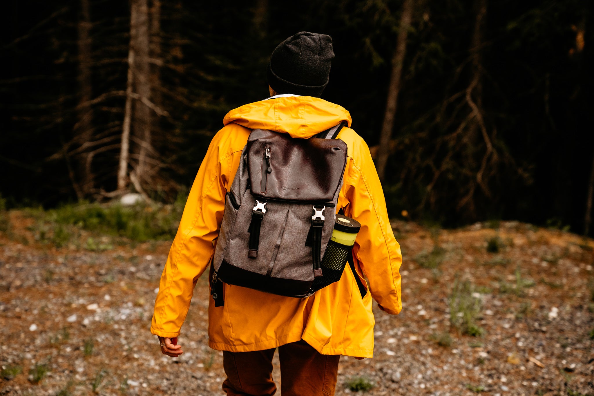 Woman in bright yellow raincoat with backpack with electric camping stove in pocket